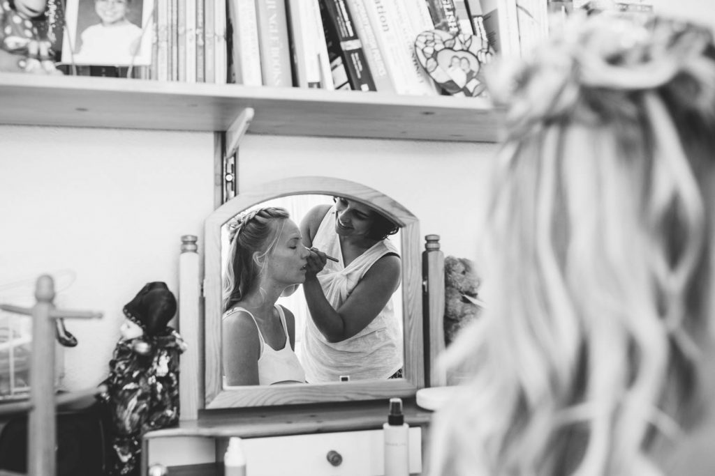 reflection in the mirror of a bridesmaid having her make up done