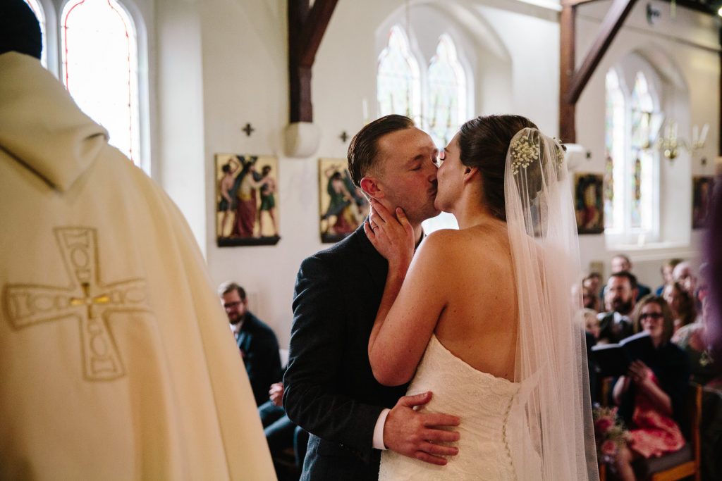 Bride and groom first kiss during church wedding ceremony