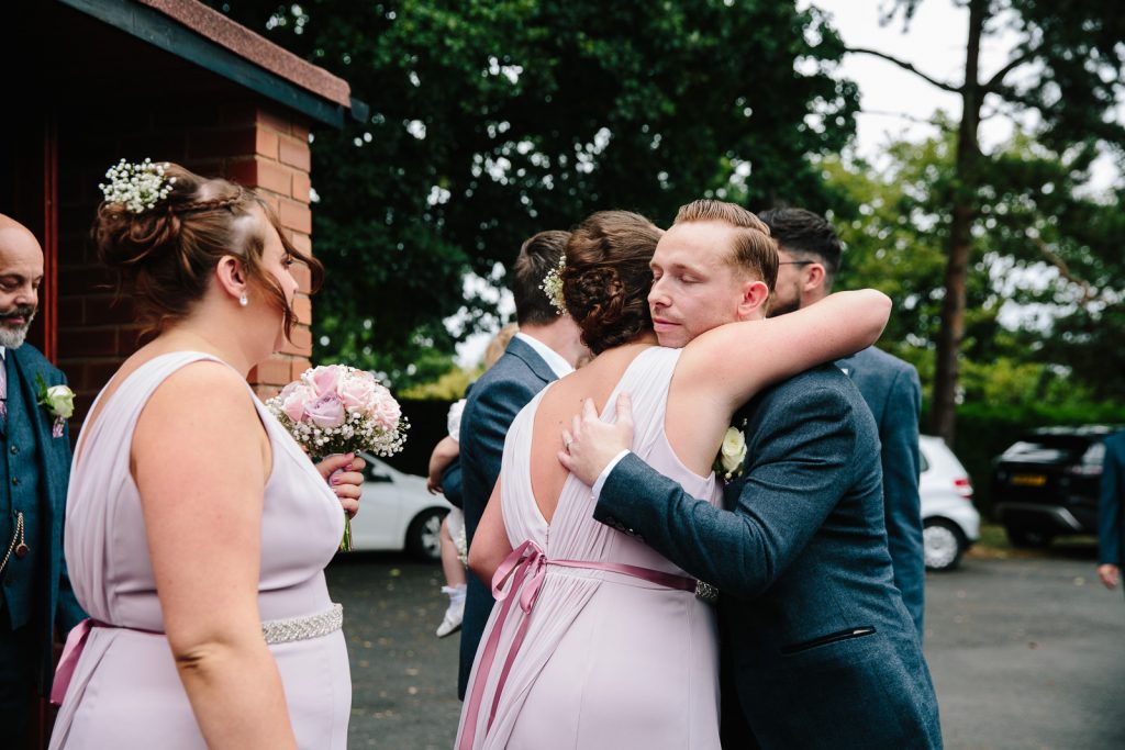 Groom hugging bridesmaid after wedding ceremony