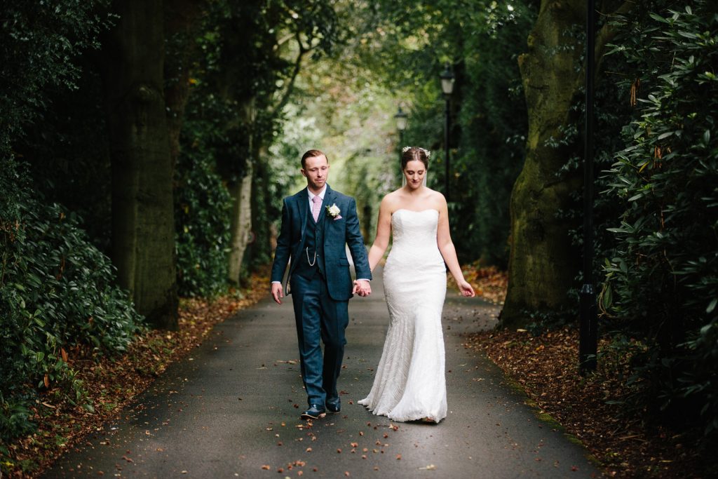 Bride and groom walking hand in hand, down the drive at Nuthurst Grange