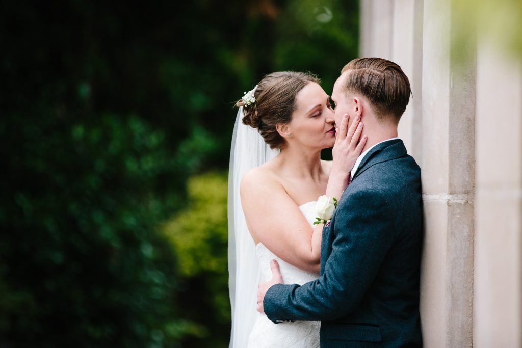 Bride and Groom kissing against a wall, Nuthurst Grange
