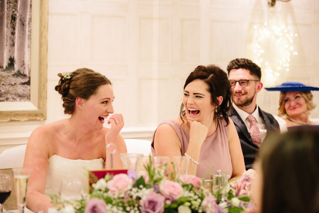 Bride and bridesmaid laughing during speeches