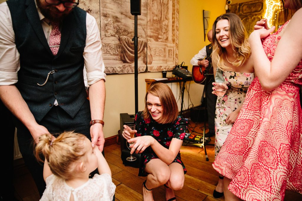 guests laughing with little girl at wedding reception, Nuthurst Grange