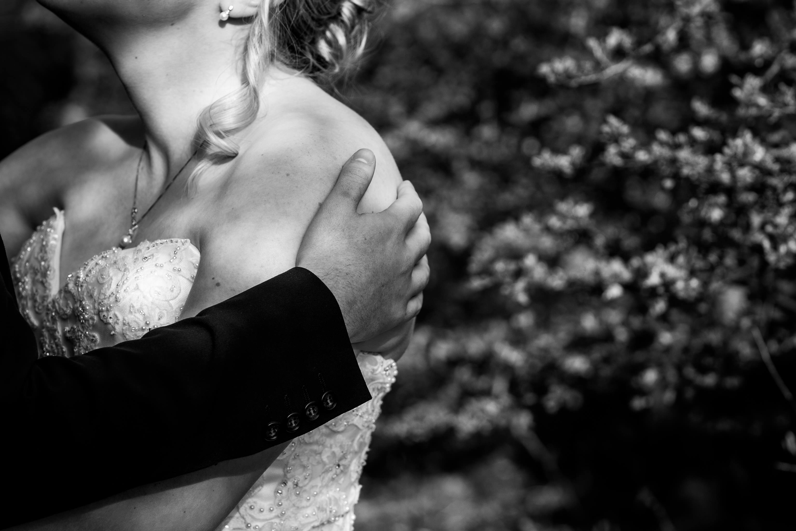 Grooms hand affectionately holding brides shoulder