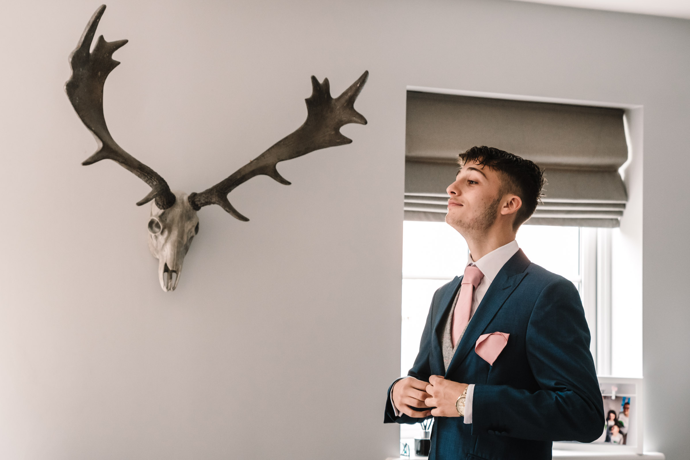 Bride's brother getting ready for Leicester wedding, staying next to antlers and skull on the wall