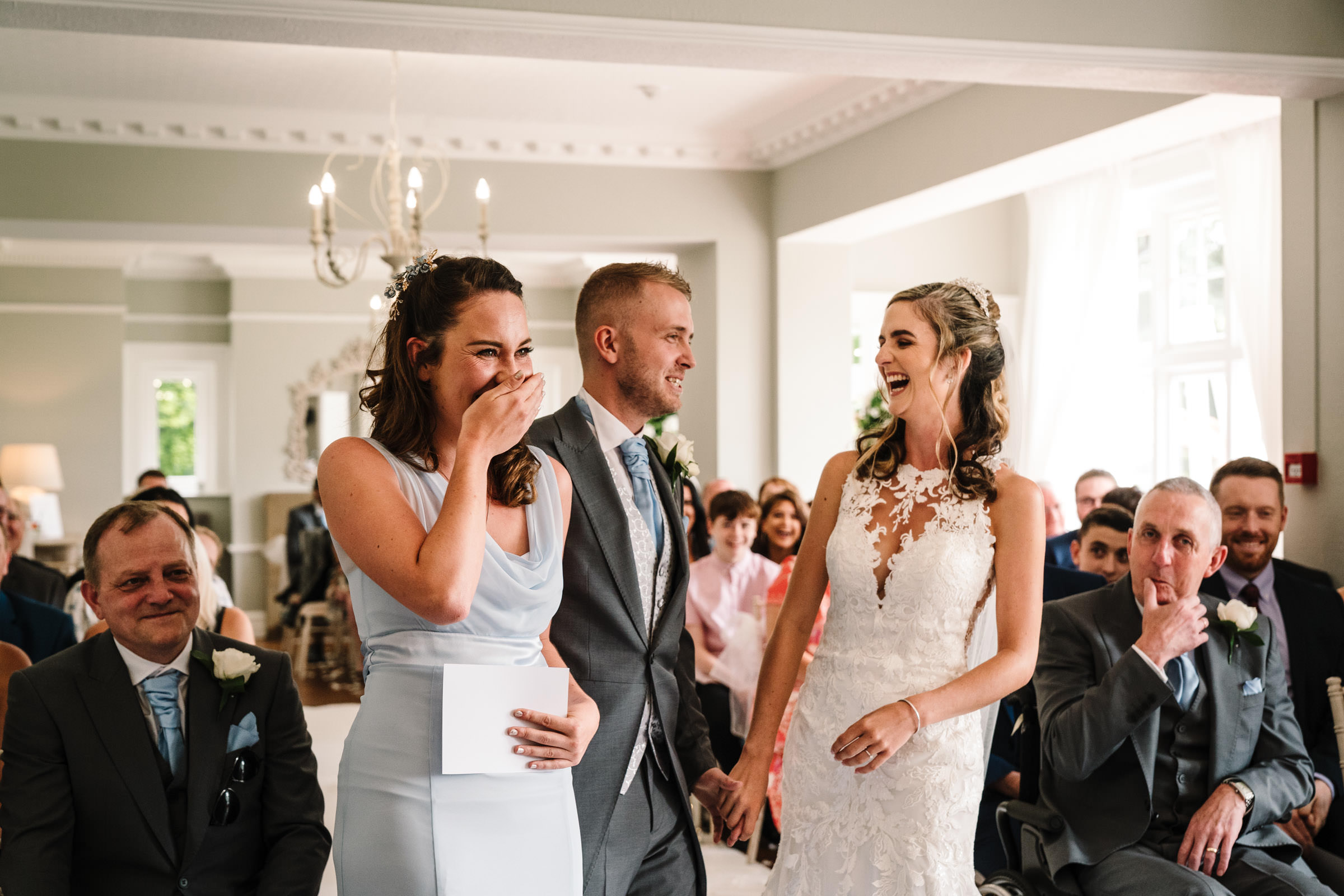 bridesmaid, bride and groom laughing during wedding ceremony