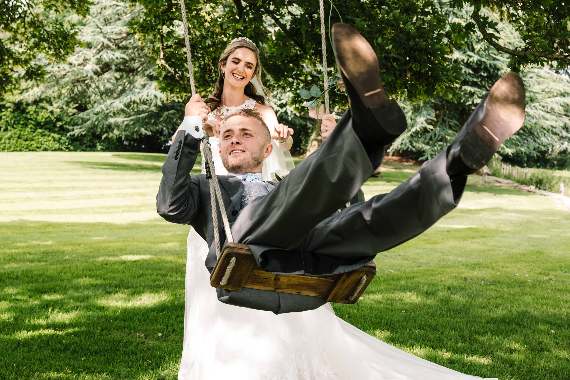 bride pushing groom on the swing at ashton lodge