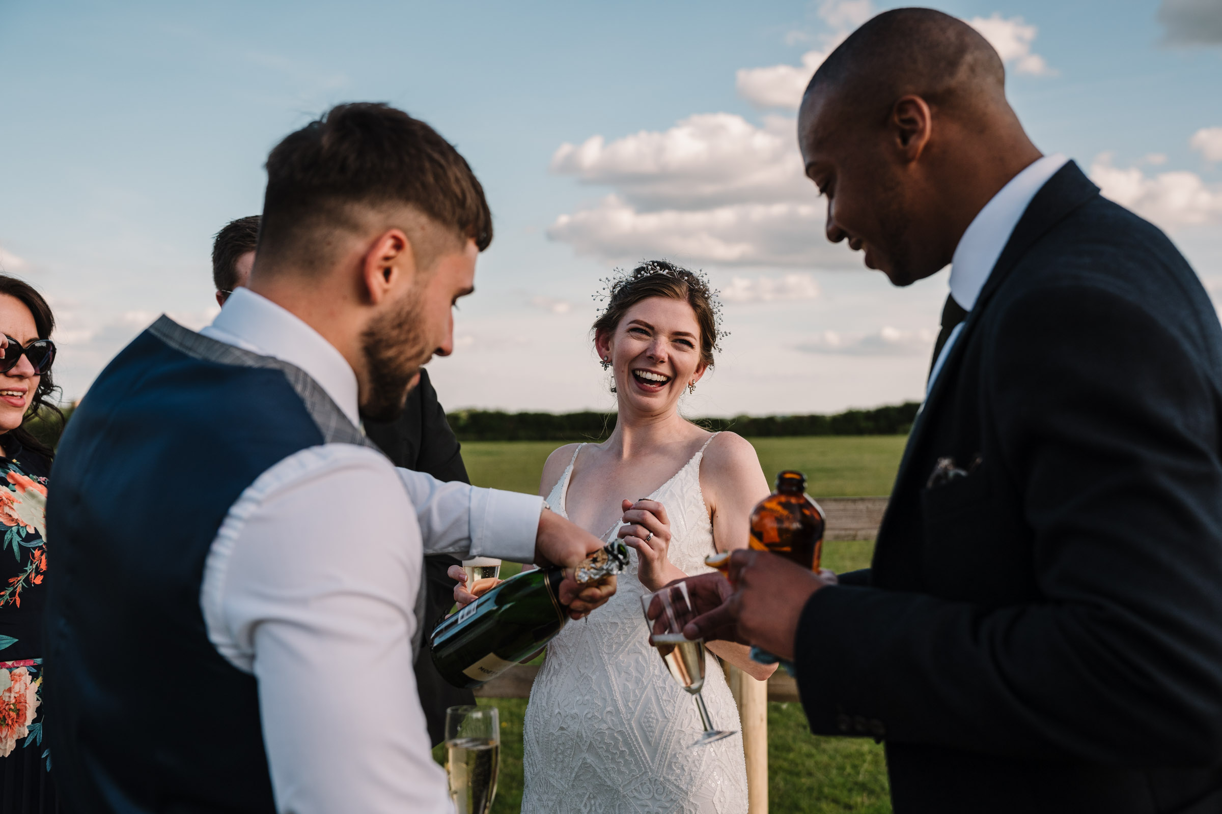 bride laughing and drinking champagne at outdoor wedding in Kenilworth